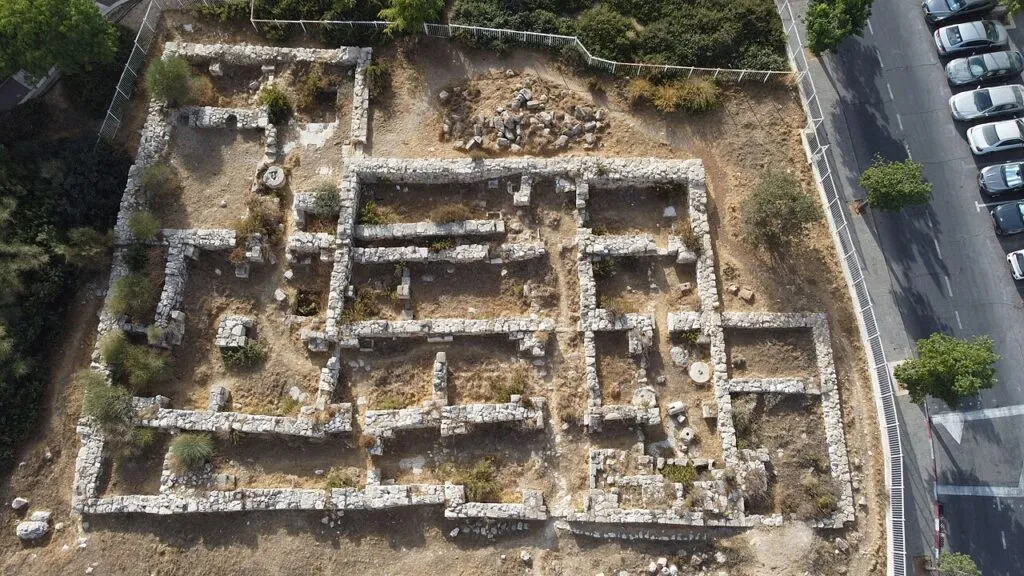 מבט מלמעלה על מנזר הצבאים בפסגת זאב מזרח: קירות אבן נמוכים שיוצרים חדרים רבים, ולצידם רחוב עם מכוניות חונות