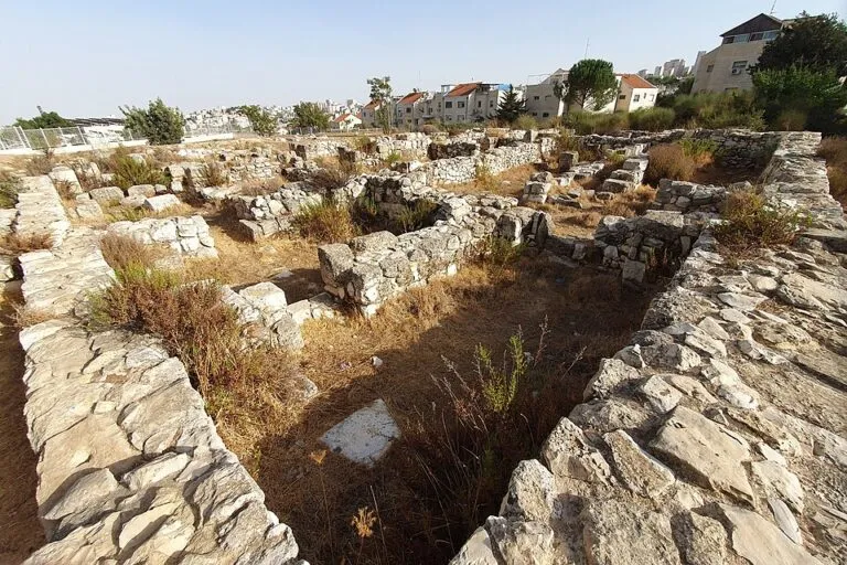 מבט מגבוה על חדר צר וארוך בין שני קירות אבן, ועוד קירות ובתים ברקע